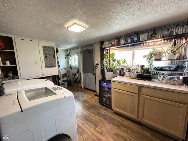 washroom featuring washing machine and dryer, wood finished floors, a textured ceiling, and beverage cooler
