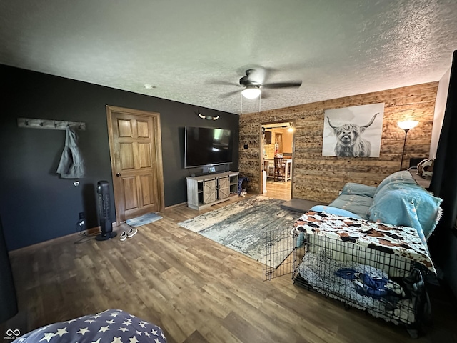 living room with a textured ceiling, ceiling fan, wood finished floors, and baseboards