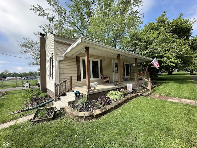 view of front facade featuring a chimney, a porch, and a front yard