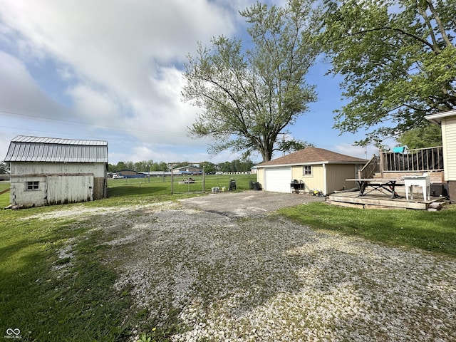 view of yard featuring an outdoor structure, a deck, and a detached garage