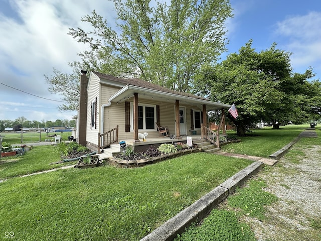 view of front of home featuring a porch, a chimney, and a front lawn