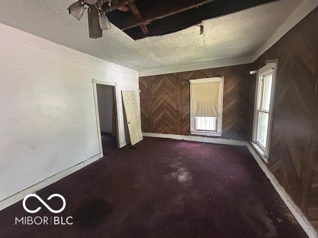 811 W 25th St, Indianapolis, IN 46208 - unfurnished room with wood walls, baseboards, a ceiling fan, and a textured ceiling