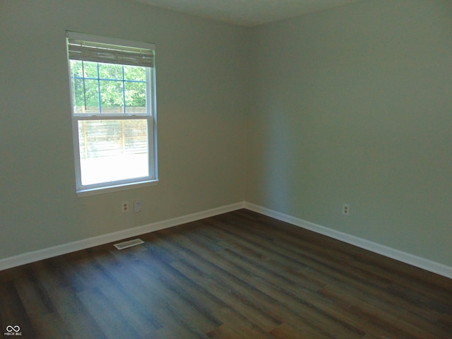 spare room with dark wood-type flooring, healthy amount of natural light, and baseboards