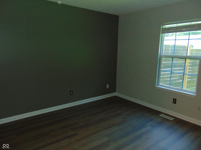 unfurnished room with healthy amount of natural light, dark wood-style flooring, and baseboards