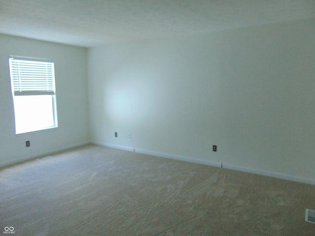spare room featuring carpet flooring and baseboards