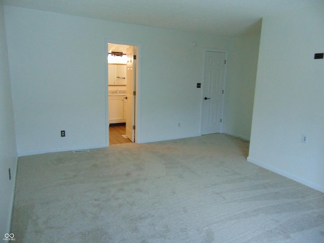 unfurnished room featuring light colored carpet and baseboards