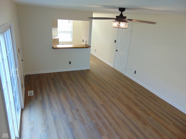 spare room featuring dark wood-type flooring, a ceiling fan, and baseboards
