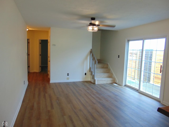unfurnished room with wood finished floors, ceiling fan, stairway, and baseboards