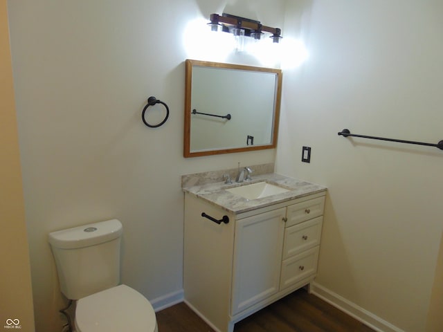 bathroom with wood finished floors, toilet, vanity, and baseboards