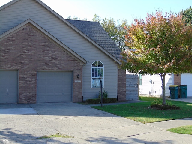 view of front of house with brick siding, driveway, roof with shingles, and a front lawn
