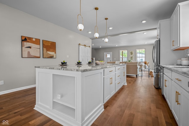 1825 E Maryland St, Indianapolis, IN 46201 - kitchen with dark wood finished floors, open floor plan, freestanding refrigerator, an island with sink, and white cabinetry