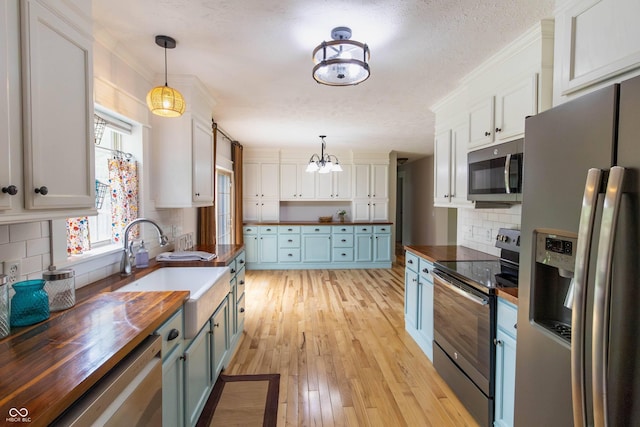 2935 N Grizzly Ln, Martinsville, IN 46151 - kitchen featuring appliances with stainless steel finishes, butcher block counters, blue cabinets, a chandelier, and light wood-style flooring