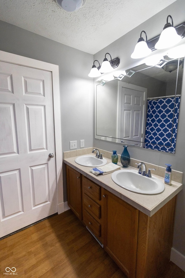 2935 N Grizzly Ln, Martinsville, IN 46151 - full bathroom featuring wood finished floors, double vanity, baseboards, and a textured ceiling