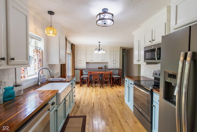 2935 N Grizzly Ln, Martinsville, IN 46151 - kitchen featuring stainless steel appliances, wooden counters, a chandelier, tasteful backsplash, and light wood finished floors