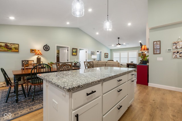1959 Sophia Ln, Seymour, IN 47274 - kitchen with light wood finished floors, lofted ceiling, decorative light fixtures, white cabinets, and a center island