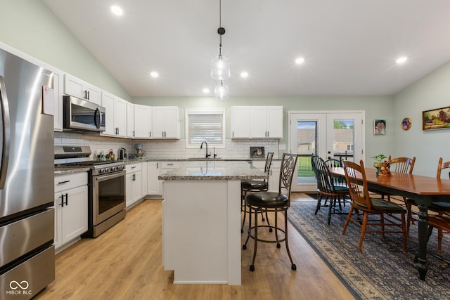 1959 Sophia Ln, Seymour, IN 47274 - kitchen with appliances with stainless steel finishes, decorative backsplash, a center island, a breakfast bar area, and vaulted ceiling
