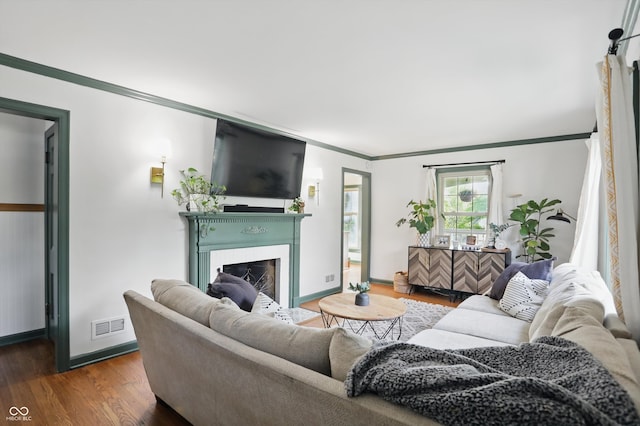 living area featuring ornamental molding, dark wood-style floors, a fireplace with flush hearth, and baseboards
