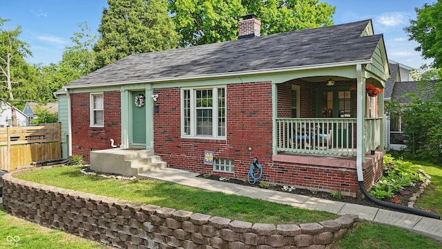 view of front facade with brick siding, fence, a chimney, and roof with shingles