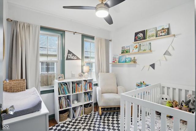 bedroom featuring a nursery area, tile patterned floors, and a ceiling fan