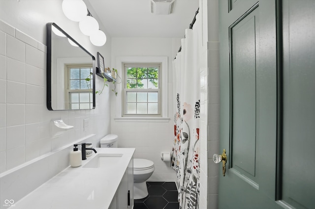 full bathroom with toilet, tile patterned flooring, tile walls, vanity, and curtained shower