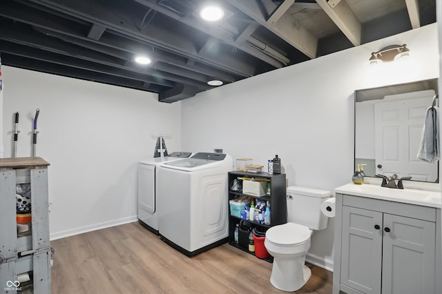 bathroom with washing machine and clothes dryer, toilet, wood finished floors, vanity, and baseboards
