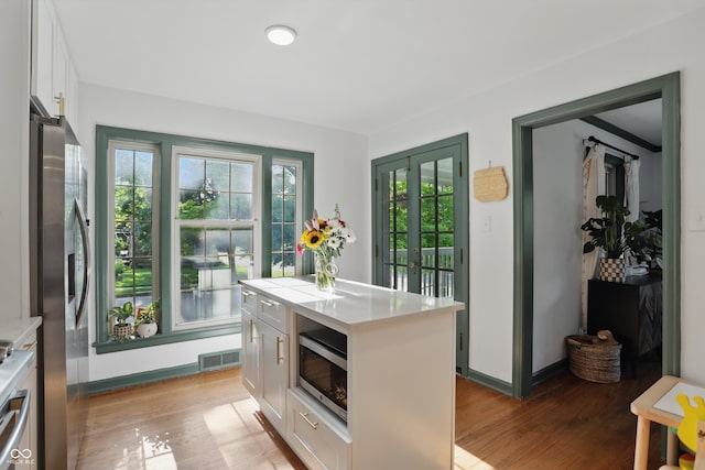 kitchen with stainless steel appliances, white cabinets, light countertops, and light wood-style flooring