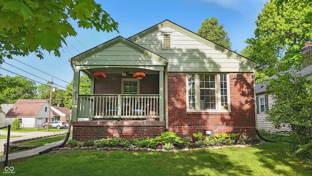 bungalow featuring brick siding, a front lawn, covered porch, and ceiling fan