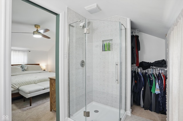 ensuite bathroom with a walk in closet, ceiling fan, a shower stall, and lofted ceiling