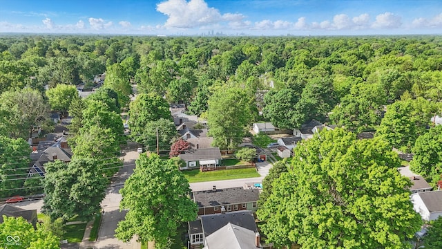 aerial view of property and surrounding area featuring a forest and nearby suburban area