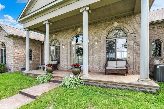 893 W 500 S, Anderson, IN 46013 - property entrance featuring a porch, brick siding, central air condition unit, a lawn, and roof with shingles