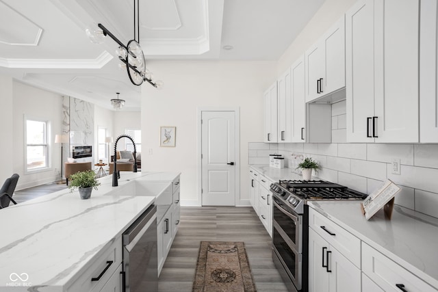 2024 Yandes St, Indianapolis, IN 46202 - kitchen with appliances with stainless steel finishes, wood finished floors, a sink, light stone countertops, and backsplash
