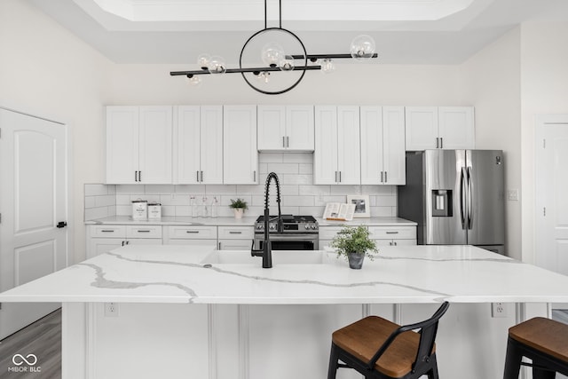 2024 Yandes St, Indianapolis, IN 46202 - kitchen featuring appliances with stainless steel finishes, tasteful backsplash, white cabinetry, a kitchen breakfast bar, and a center island with sink