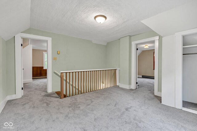 1437 S 725 W, Tipton, IN 46072 - corridor featuring an upstairs landing, carpet flooring, a textured ceiling, baseboard heating, and vaulted ceiling