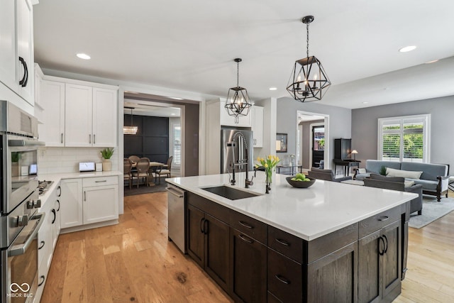 1616 N Delaware St, Indianapolis, IN 46202 - kitchen featuring appliances with stainless steel finishes, white cabinets, dark brown cabinets, a sink, and light wood-type flooring
