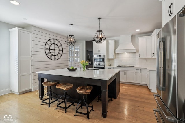 1616 N Delaware St, Indianapolis, IN 46202 - kitchen with appliances with stainless steel finishes, custom range hood, light countertops, a breakfast bar area, and recessed lighting
