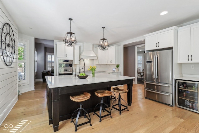 1616 N Delaware St, Indianapolis, IN 46202 - kitchen with appliances with stainless steel finishes, wine cooler, custom exhaust hood, light wood-style flooring, and light countertops