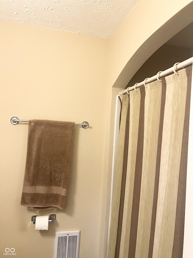 bathroom with a textured ceiling and a shower with shower curtain