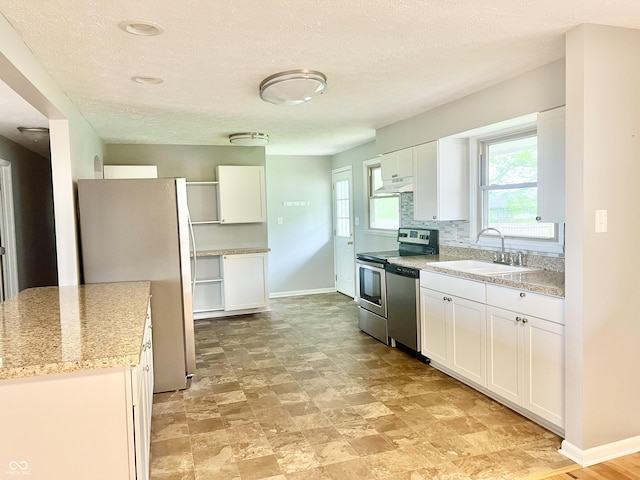 kitchen featuring stainless steel appliances, a sink, under cabinet range hood, white cabinetry, and a textured ceiling