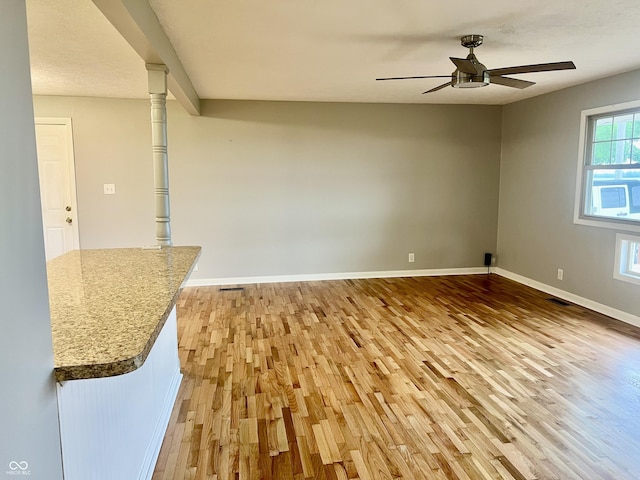 spare room featuring light wood finished floors, a ceiling fan, and baseboards