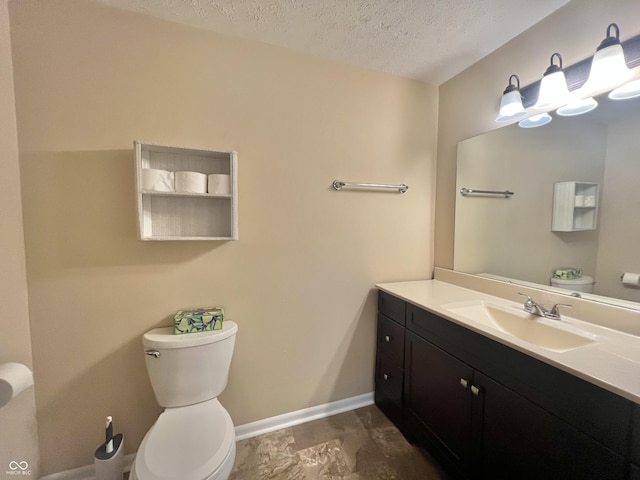 half bath with toilet, baseboards, a textured ceiling, and vanity