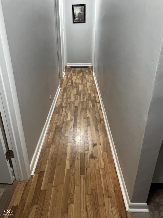 hall with wood-type flooring and baseboards