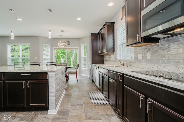 1274 Timber Bluff Rd, Westfield, IN 46074 - kitchen with stainless steel microwave, tasteful backsplash, light stone counters, decorative light fixtures, and a sink