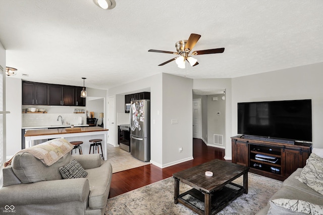 5041 Millwright Ct, Indianapolis, IN 46254 - living room with ceiling fan, light wood-style flooring, a textured ceiling, and baseboards