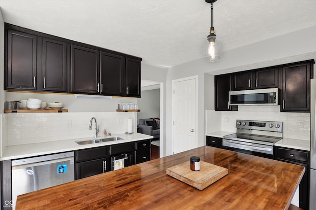 5041 Millwright Ct, Indianapolis, IN 46254 - kitchen featuring appliances with stainless steel finishes, butcher block counters, a sink, dark cabinetry, and a textured ceiling