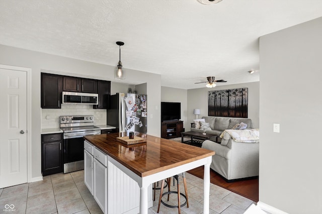 5041 Millwright Ct, Indianapolis, IN 46254 - kitchen featuring stainless steel appliances, light tile patterned floors, wood counters, and backsplash