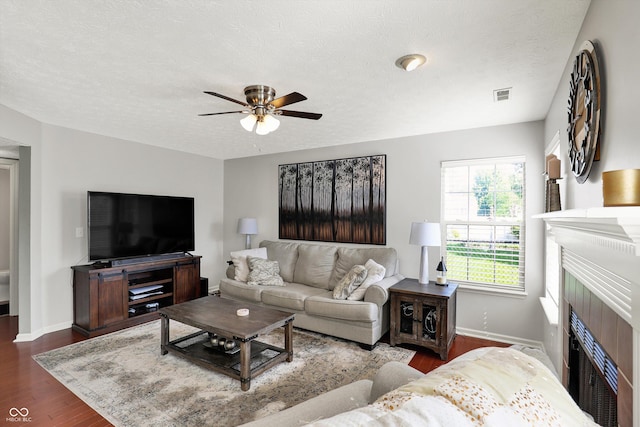 5041 Millwright Ct, Indianapolis, IN 46254 - living room with dark wood-style flooring, a fireplace, ceiling fan, baseboards, and a textured ceiling