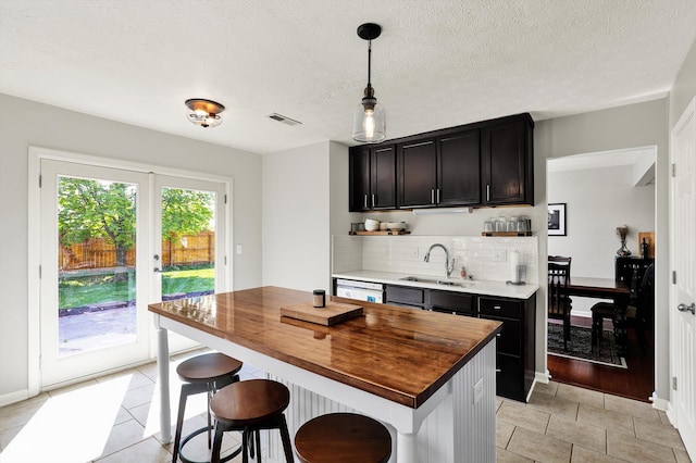 5041 Millwright Ct, Indianapolis, IN 46254 - kitchen with a sink, wooden counters, light tile patterned flooring, tasteful backsplash, and a breakfast bar area