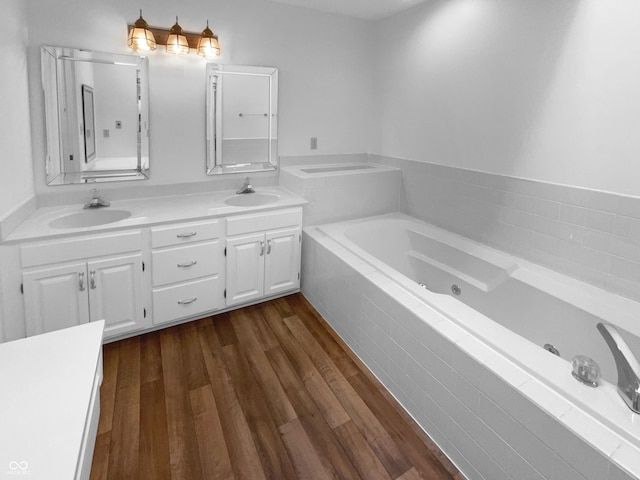 bathroom with wood finished floors, a jetted tub, and double vanity