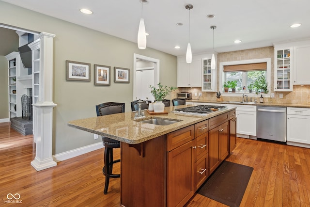 8330 Claridge Rd, Indianapolis, IN 46260 - kitchen with stainless steel appliances, a sink, light wood finished floors, a kitchen breakfast bar, and decorative backsplash