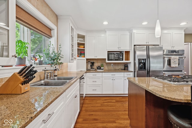 8330 Claridge Rd, Indianapolis, IN 46260 - kitchen featuring appliances with stainless steel finishes, a sink, wood finished floors, white cabinetry, and decorative light fixtures